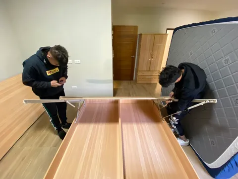 兩位師傅在空房間拆解床架
